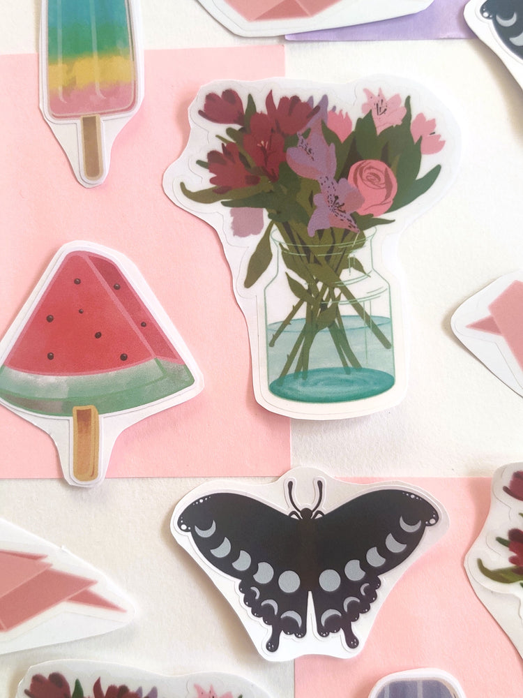 handmade illustrated stickers are laid out on a pastel checkered background